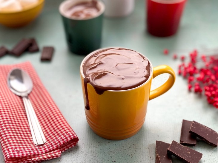 Uma xícara contendo chocolate quente com 3 ingredientes.