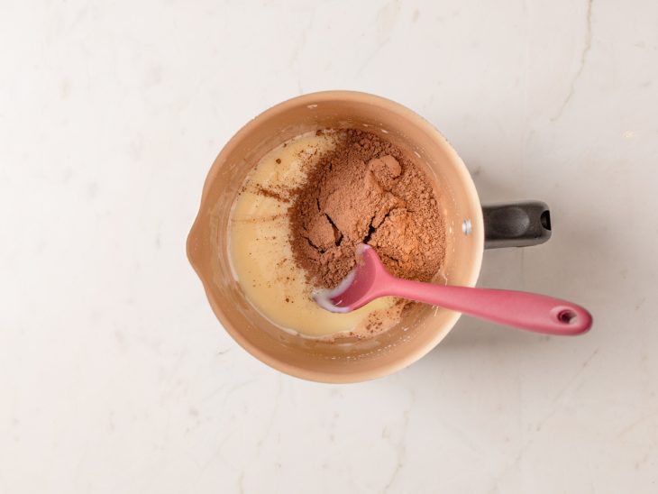 Uma leiteira com leite condensado e chocolate em pó.