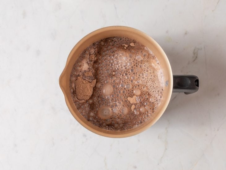 Leite com achocolatado em pó em uma leiteira.