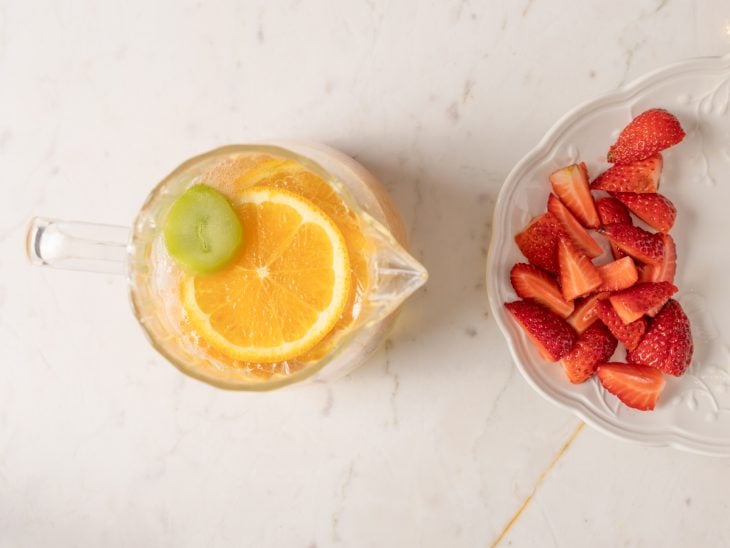 Frutas sendo adicionadas na jarra com espumante e água tônica.