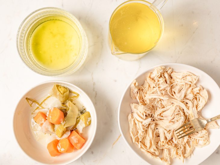 tigela com frango desfiado. Tigela com legumes cozidos. Tigela com caldo de frango.