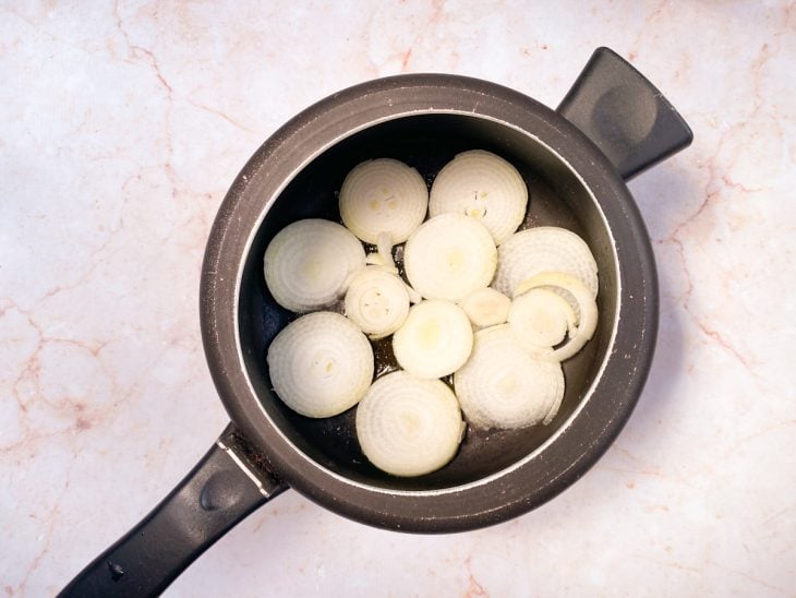 Uma panela de pressão com azeite e uma camada de cebolas.