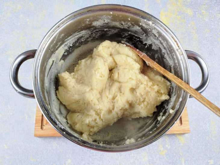 Massa da cozinha sendo amassada por uma colher de pau.