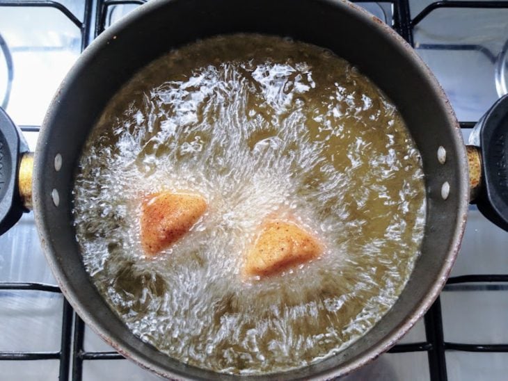 Coxinhas sendo fritas no óleo quente.