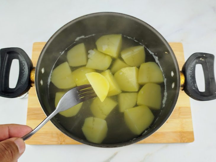 Uma panela com água e as batatas cozidas.