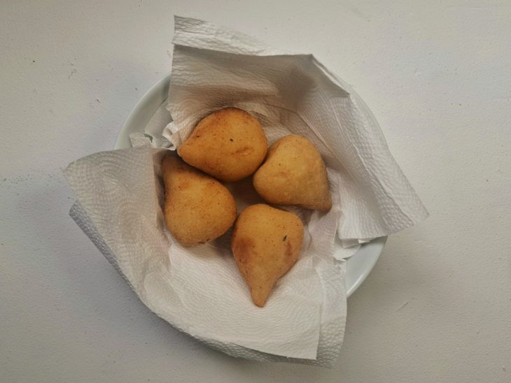 Uma tigela forrada com papel-toalha e coxinhas após fritar.