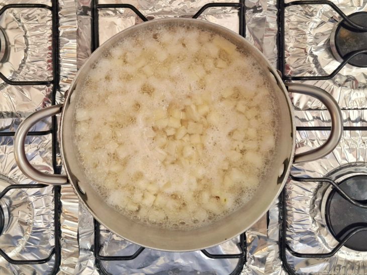 Uma panela com abacaxi, açúcar e água.