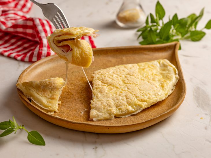 Crepioca recheada com presunto e queijo com um pedaço cortado mostrando o recheio.