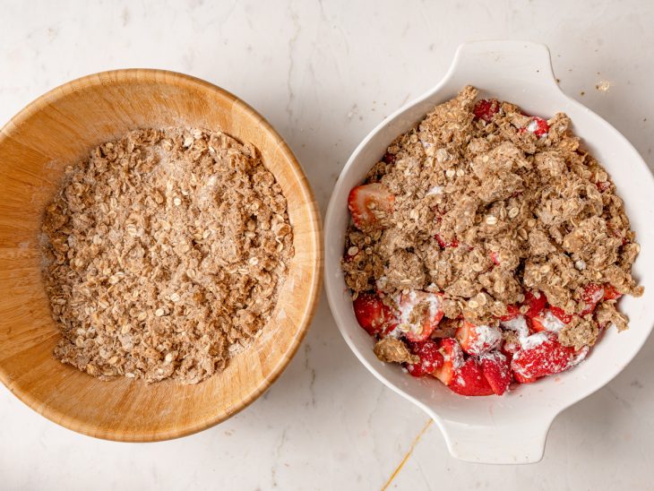 Recipiente com a camada de frutas e o crumble sendo colocado por cima.