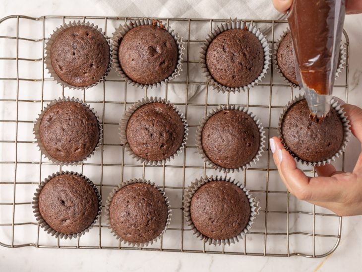 Cupcakes sendo decorados com a ganache.