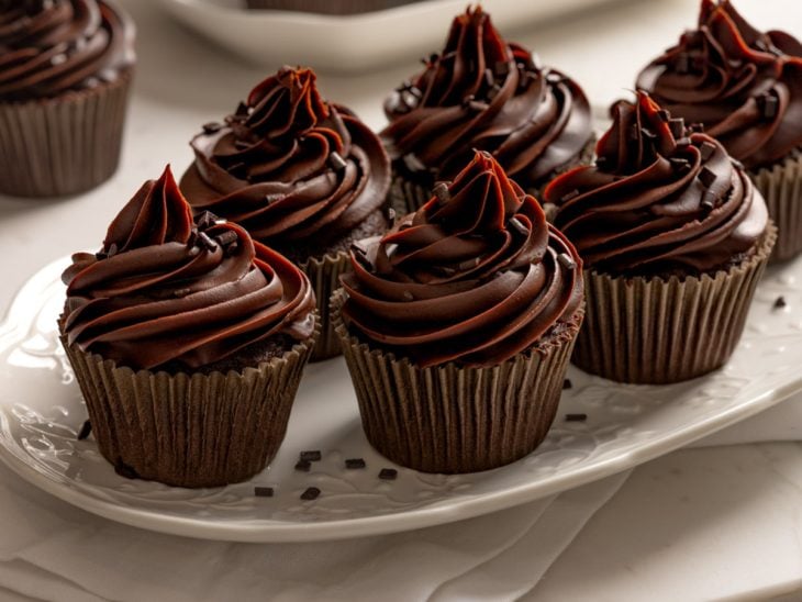 Um prato contendo cupcakes de chocolate com ganache.