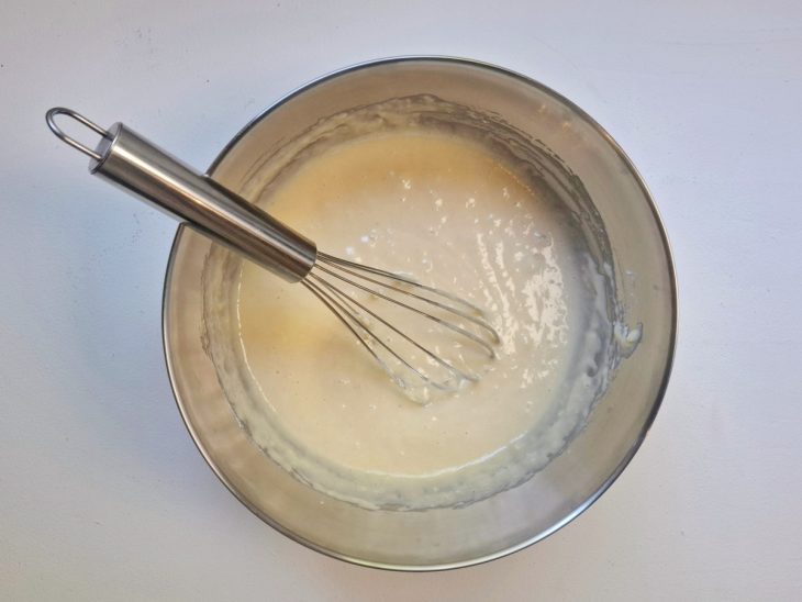 Mistura do liquidificador em uma tigela com farinha e fermento incorporados.