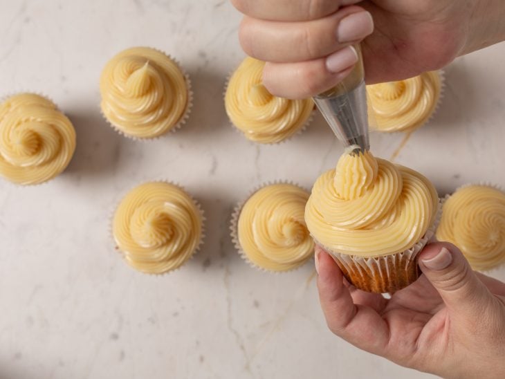 Cupcakes finalizados com cobertura no bico de confeitar.