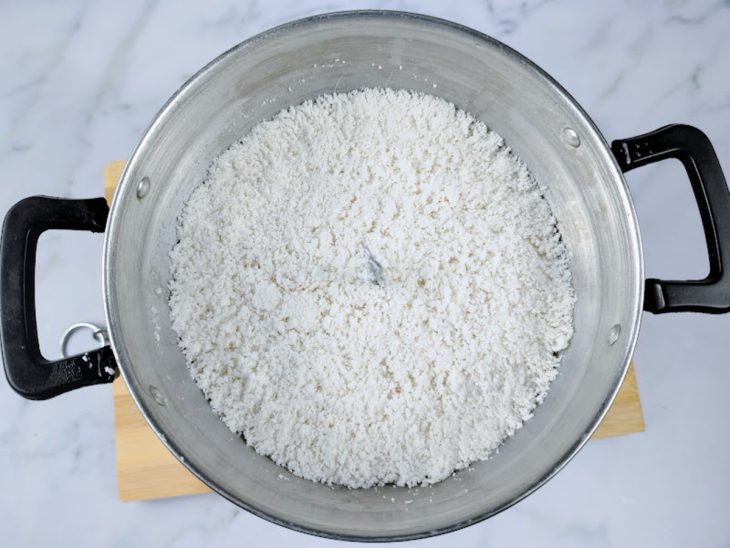 Uma cuscuzeira contendo flocão de arroz hidratada.