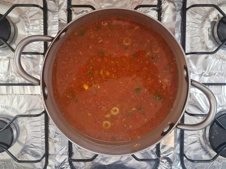 Temperos, molho de tomate e água adicionados na panela.