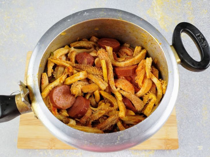 Calabresa, bucho e temperos adicionados na panela.