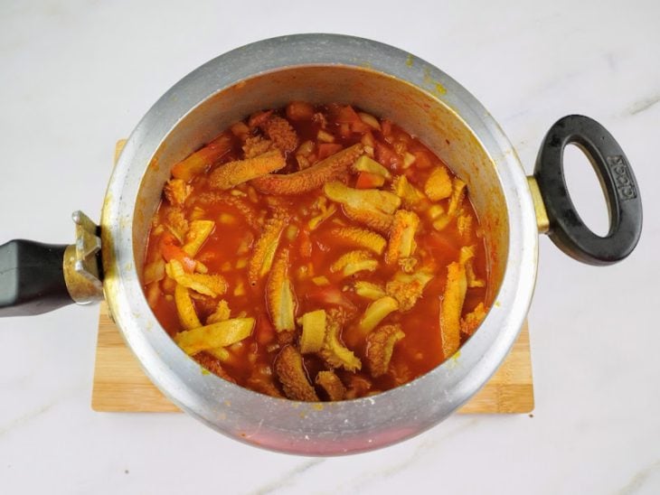 Uma panela de pressão com bucho, cebola, tomate, temperos e água.