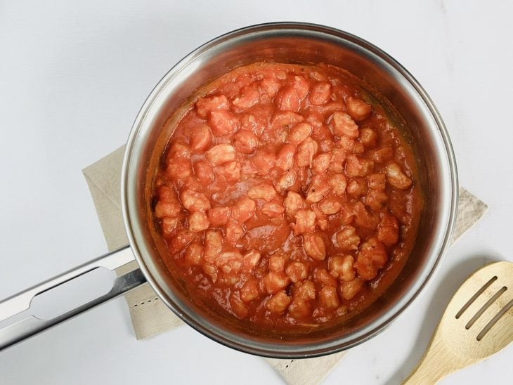 Pimenta, molho de tomate, colorau e sal adicionados a panela com camarão.