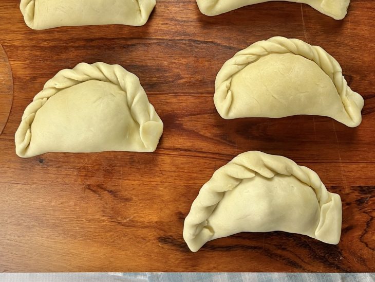 Uma tábua com empanadas prontas para assar.