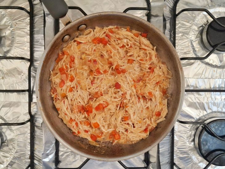 Frigideira com frango desfiado, tomate, pimentão e temperos.