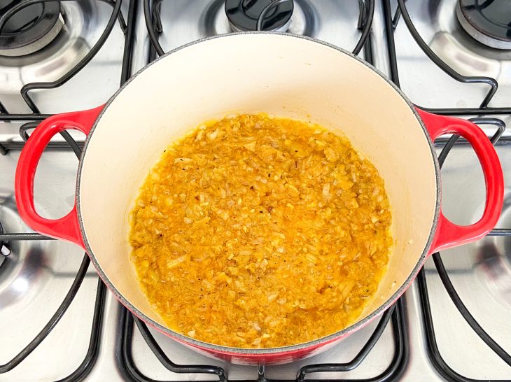 Manteiga, cebola, alho, pimenta-do-reino, pimenta calabresa, açafrão e colorau em uma panela.