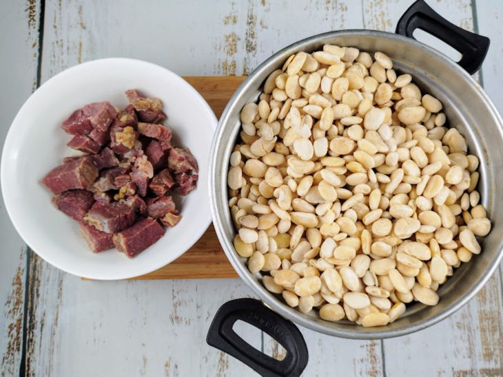 panela com fava ferventada e prato com charque dessalgado