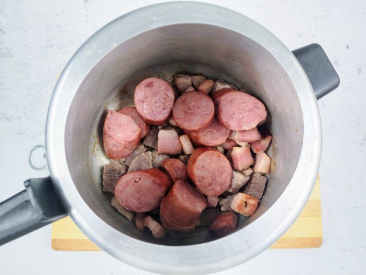 Uma panela de pressão com calabresa, carne e bacon.