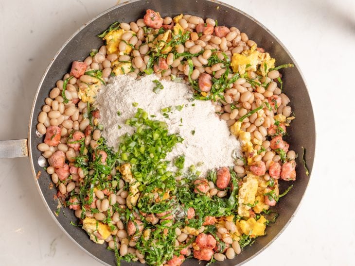 Frigideira com a junção de todos os ingredientes do feijão-tropeiro.