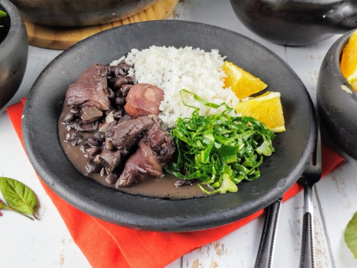 Um prato com a feijoada rápida servida com acompanhamentos.