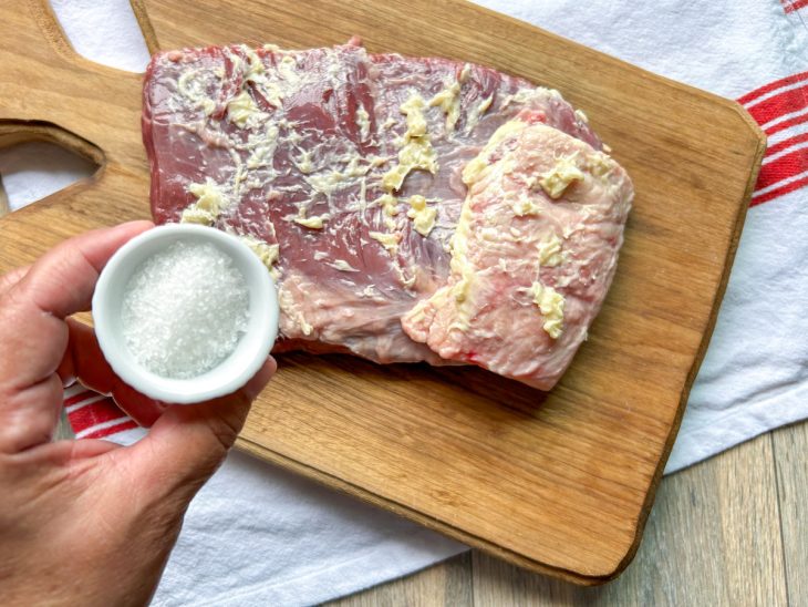 Mistura de alho e manteiga espalhada sobre a carne, e recipiente com sal para ser adicionado.