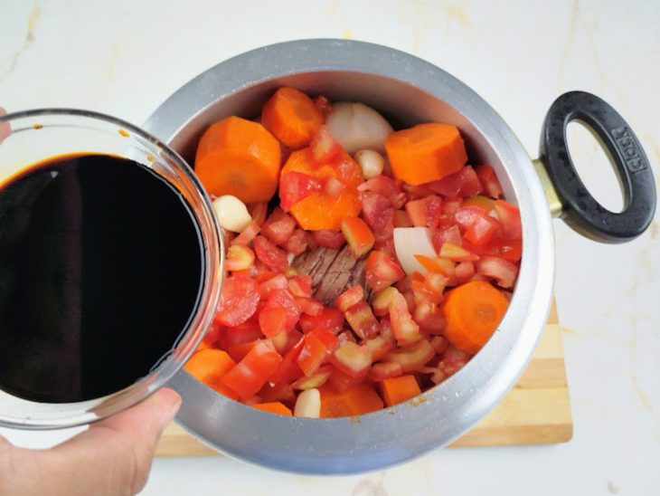 Uma panela de pressão com legumes, carne e temperos.