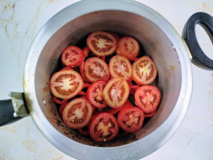 Uma panela de pressão com uma camada de cebola, pimentões e tomate.