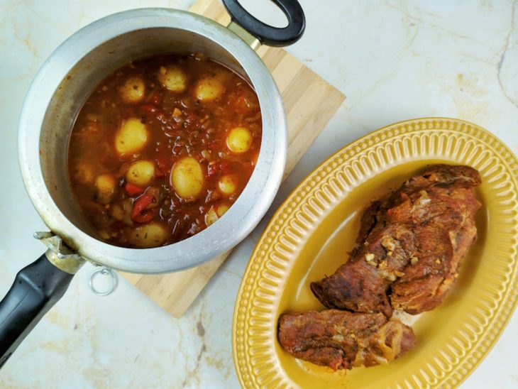 Uma panela de pressão com as batatas cozinhando e uma travessa com a fraldinha separada.