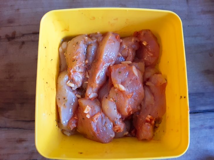 pedaços de frango já temperados e marinando em um recipiente de acrílico