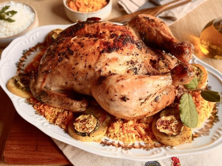 Frango pronto para consumo em um prato decorado com farofa.