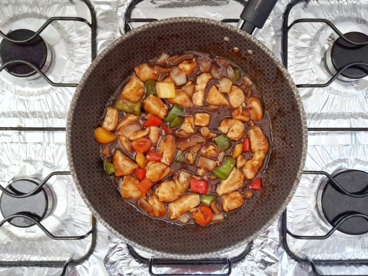 Cubos de frango, água e molho de soja adicionados na frigideira.