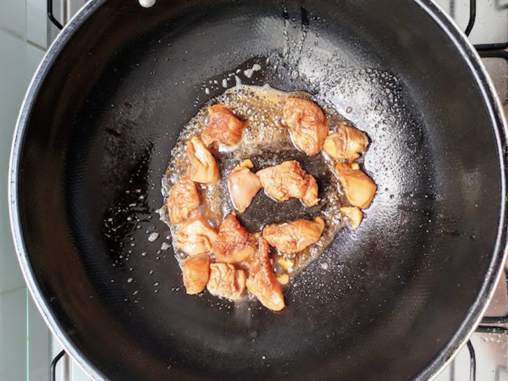 Panela wok com óleo de gergelim e o frango cortado.