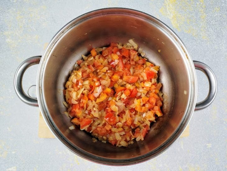 Uma panela com cebola e tomate.