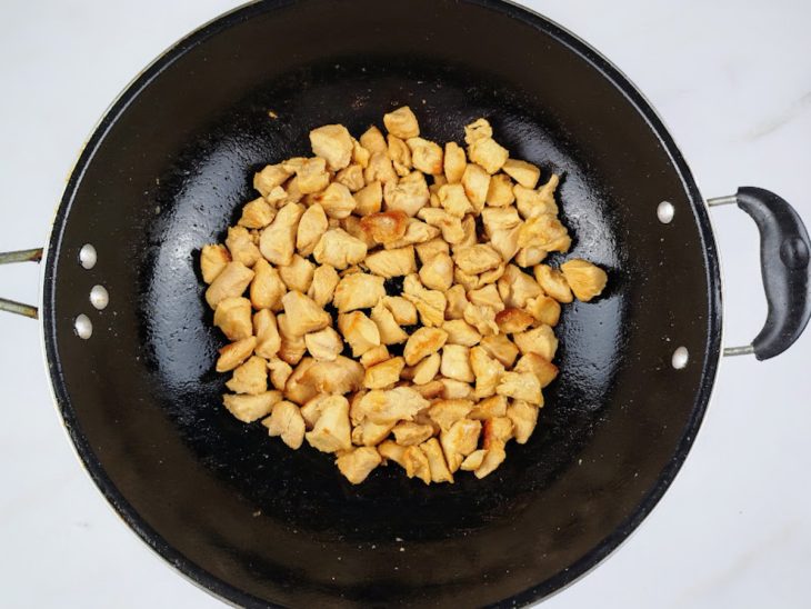 Cubos de frango temperados e refogados em uma frigideira com azeite.