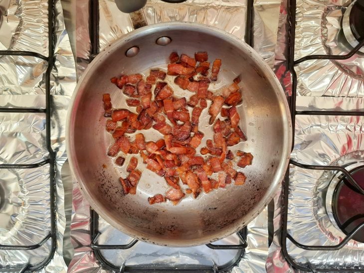 Uma frigideira fritando cubinhos de bacon.