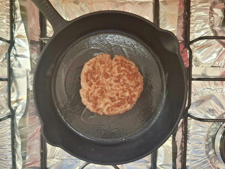 Uma frigideira fritando um hambúrguer de carne.