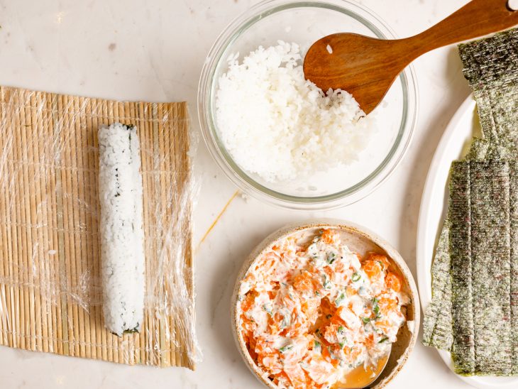 Sushi enrolado com a esteira, com arroz em destaque por fora.