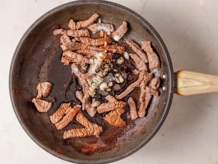 Frigideira com tirinhas de carne temperadas fritando.