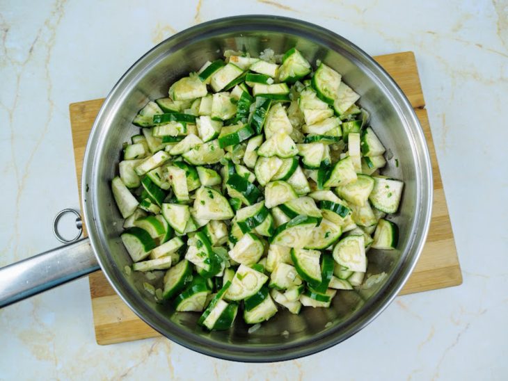 Uma frigideira com jiló, azeite, cebola, alho e cheiro-verde.