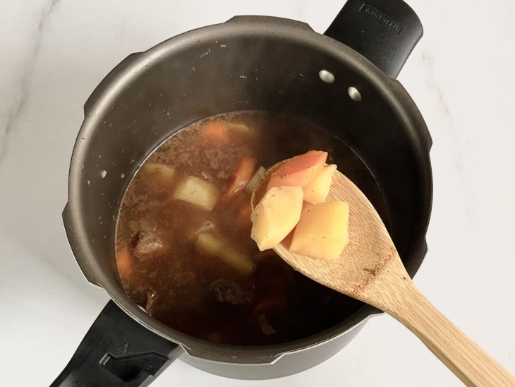 cubos de carne, batatas e cenouras cozinhando na panela de pressão