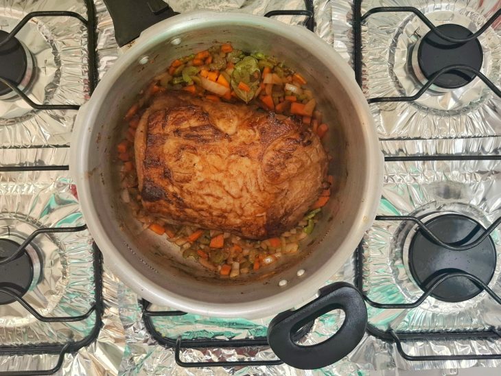 Uma panela de pressão com lagarto e legumes refogando.