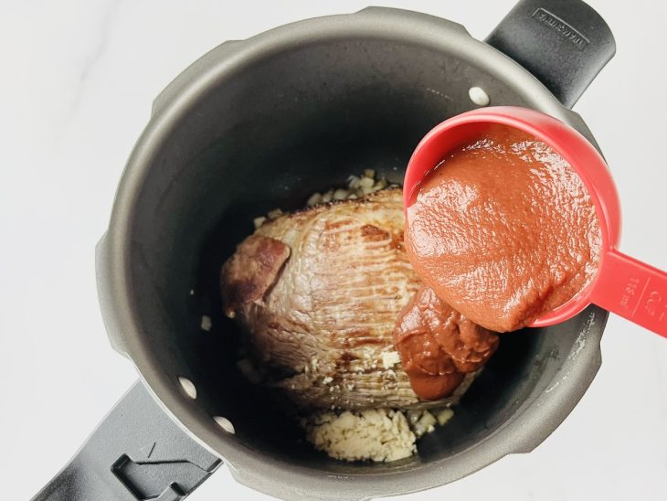 Sal, pimenta, molho de tomate e água adicionados a panela de pressão.