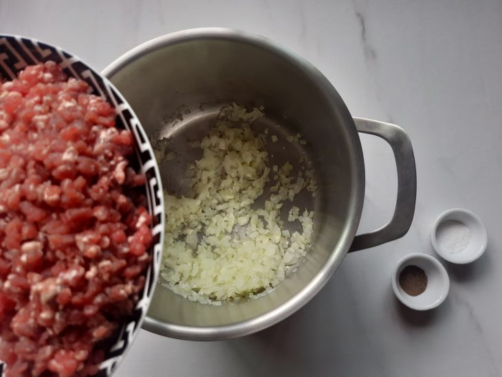 Carne moída e temperos para serem adicionados a panela com cebola e alho.