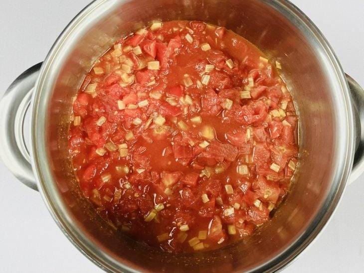 Uma panela com azeite, cebola, alho, tomate, pimentão e temperos.