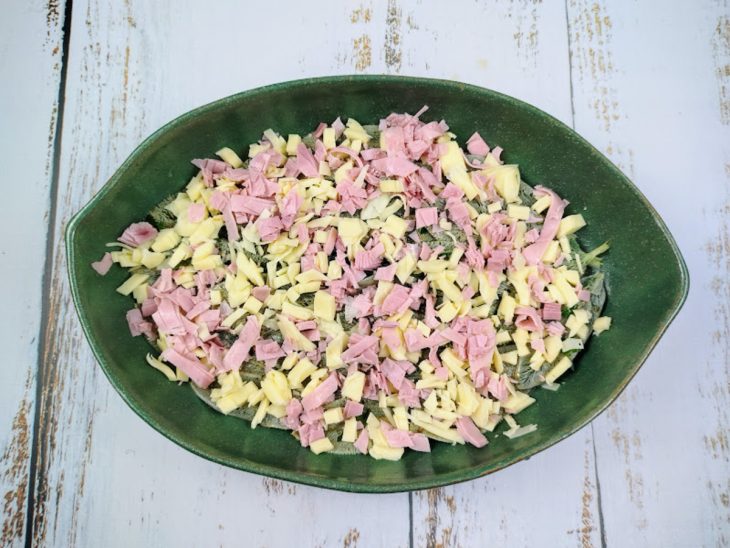 Um refratário com uma camada de peixinhos da horta e outra de presunto e queijo.